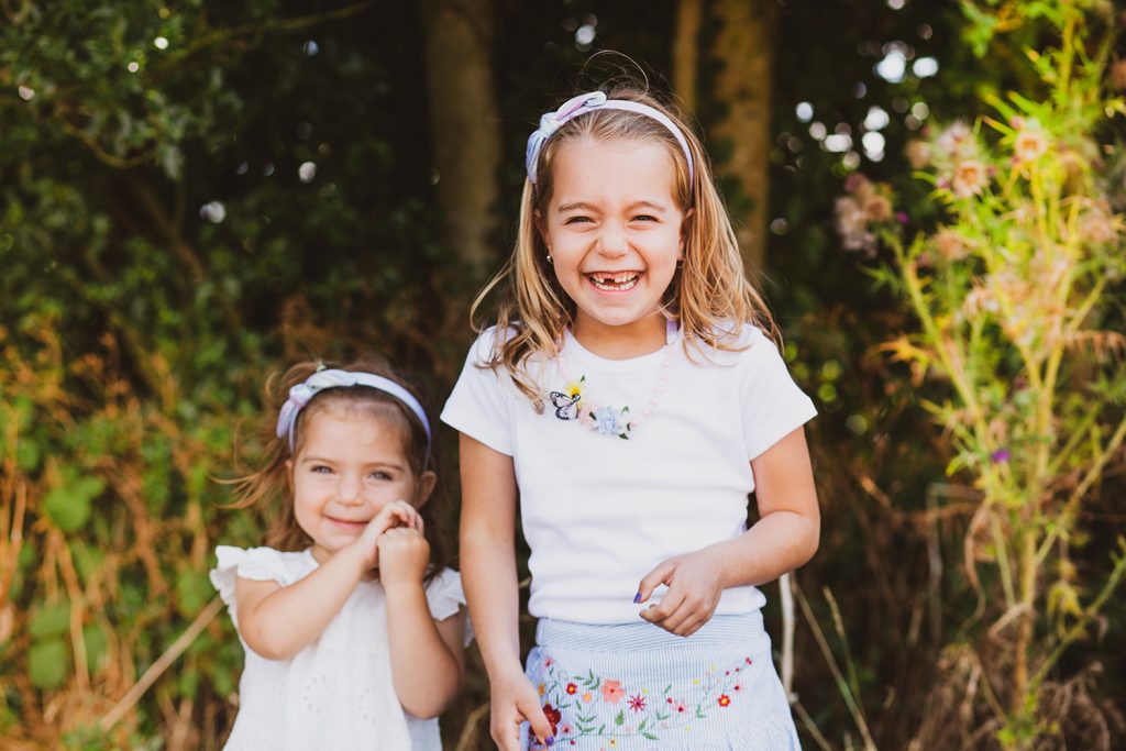 Two sisters laughing outside on a summer's day