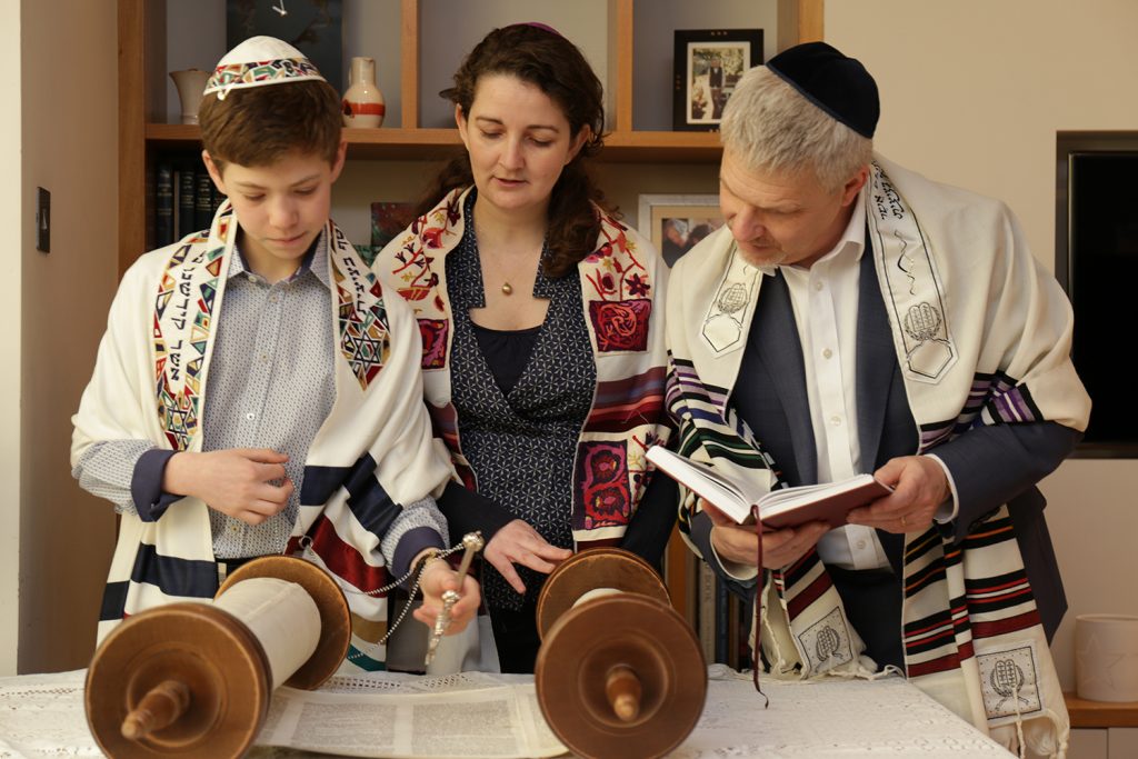 father and son reading the Torah with the lady rabbi