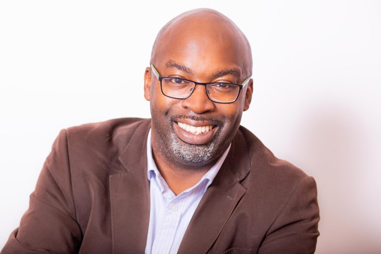 Man in glasses and brown jacket smiling
