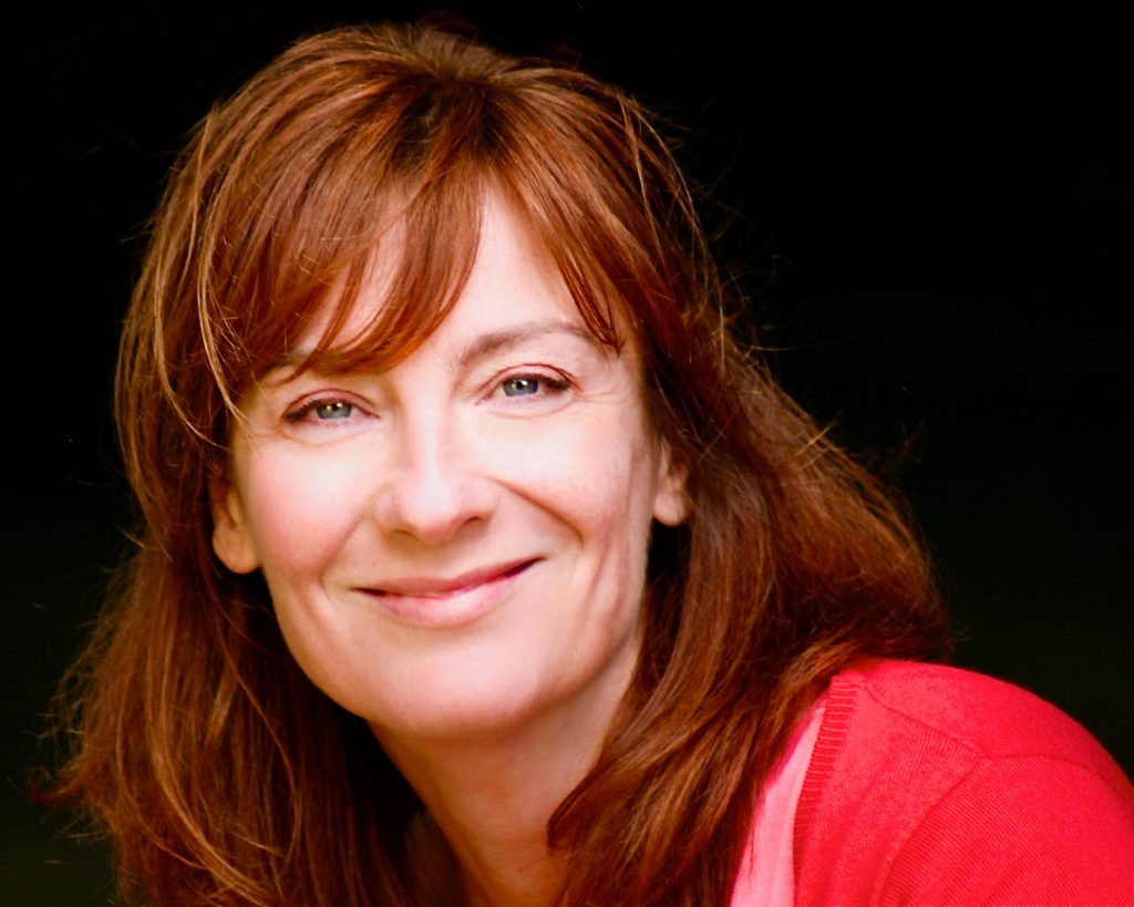 Dark haired actress wearing a red top smiling
