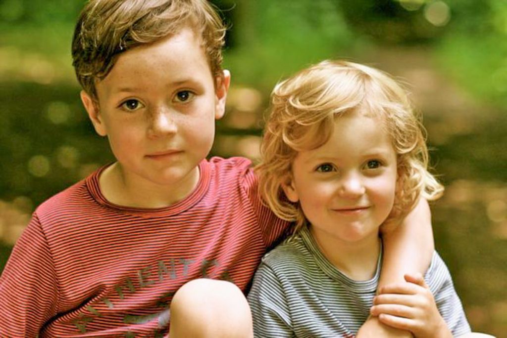 Two brothers sitting in the woods together arm in arm