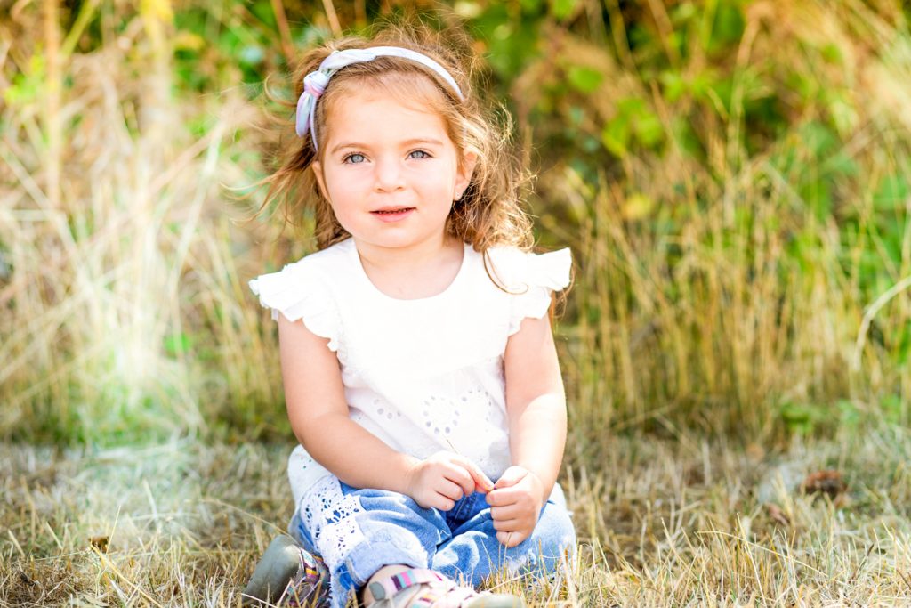 Young child with white top sitting on the grass