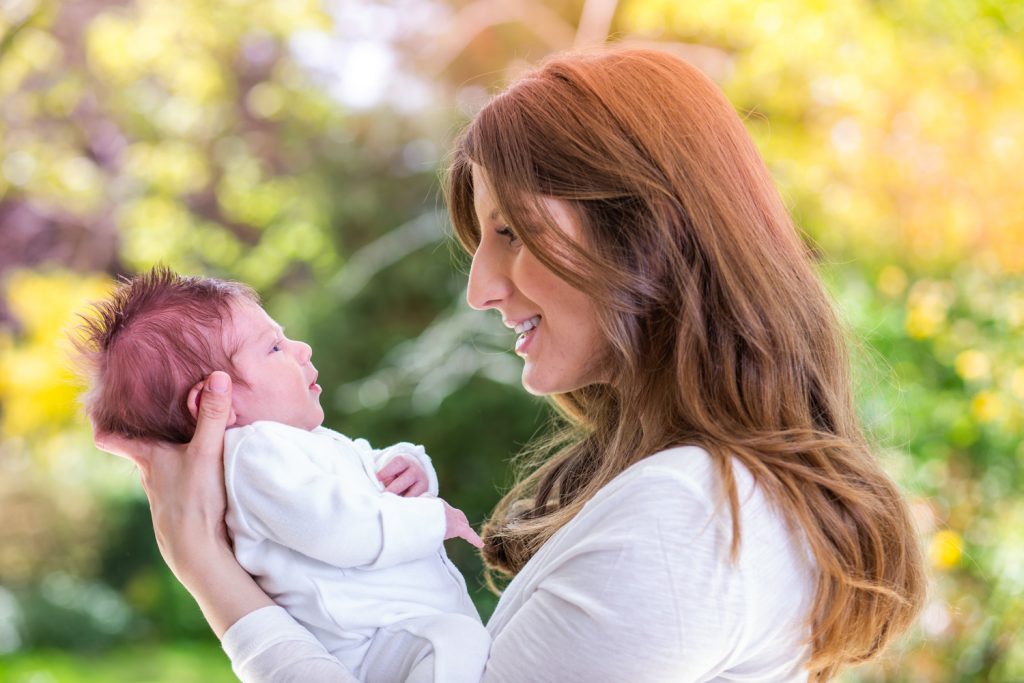 Lady with long brown hair gazing at her new born baby