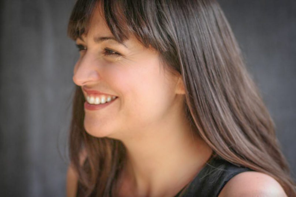 Beautiful woman with long dark hair smiling to someone off camera