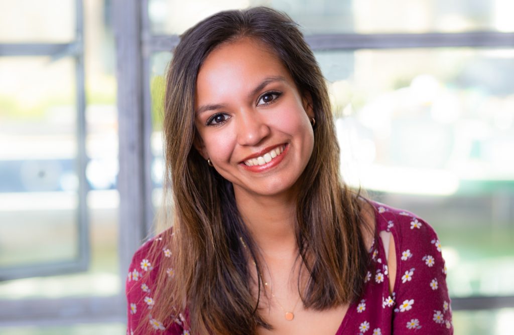 Friendly woman with warm smile standing in front of office window smiling