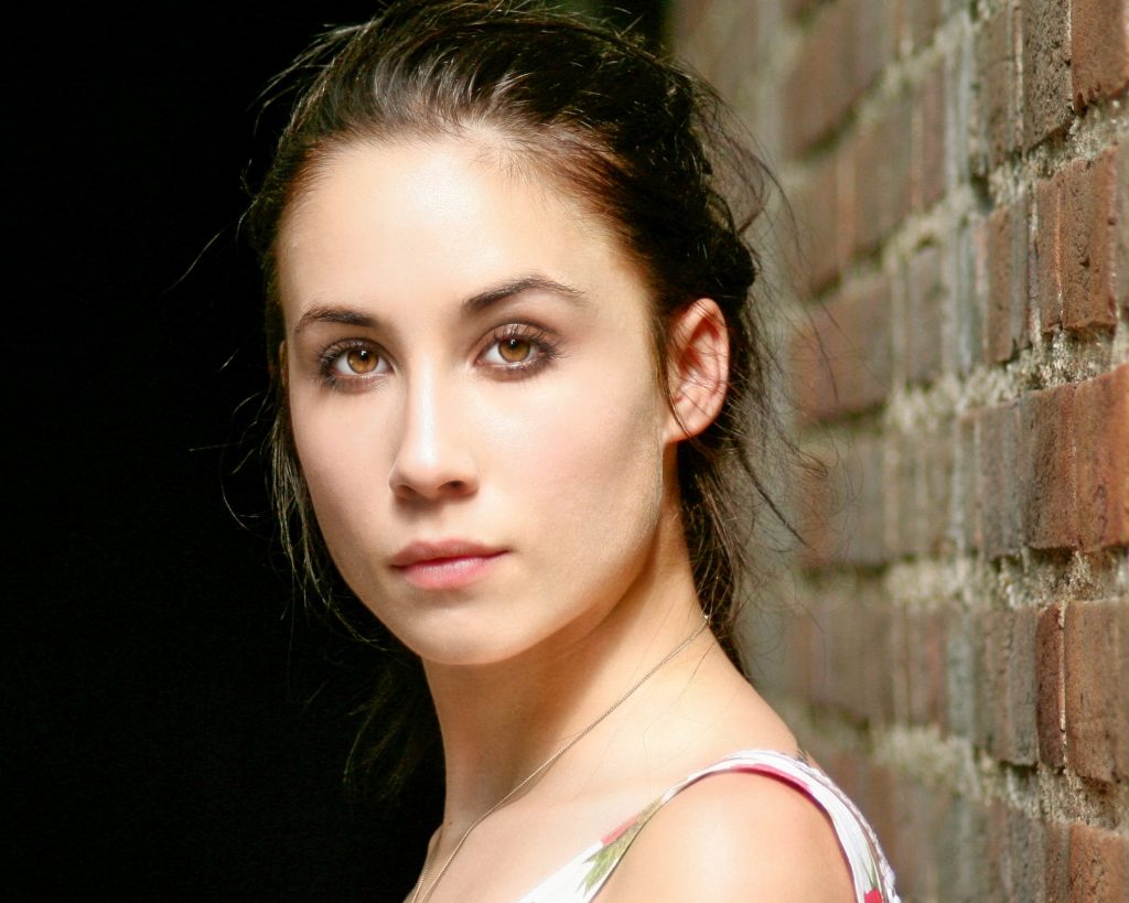young beautiful woman standing against a wall