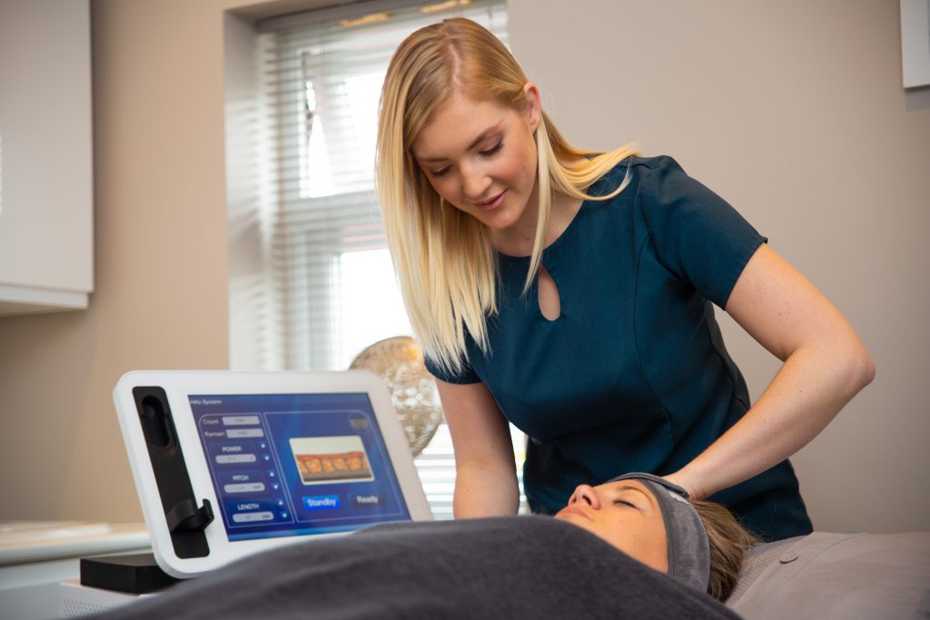 Blonde beauty therapist working on woman lying on table with machine