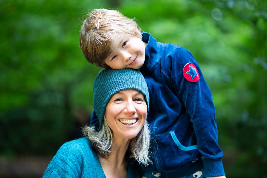 A mum and son hanging out in the woods smiling together