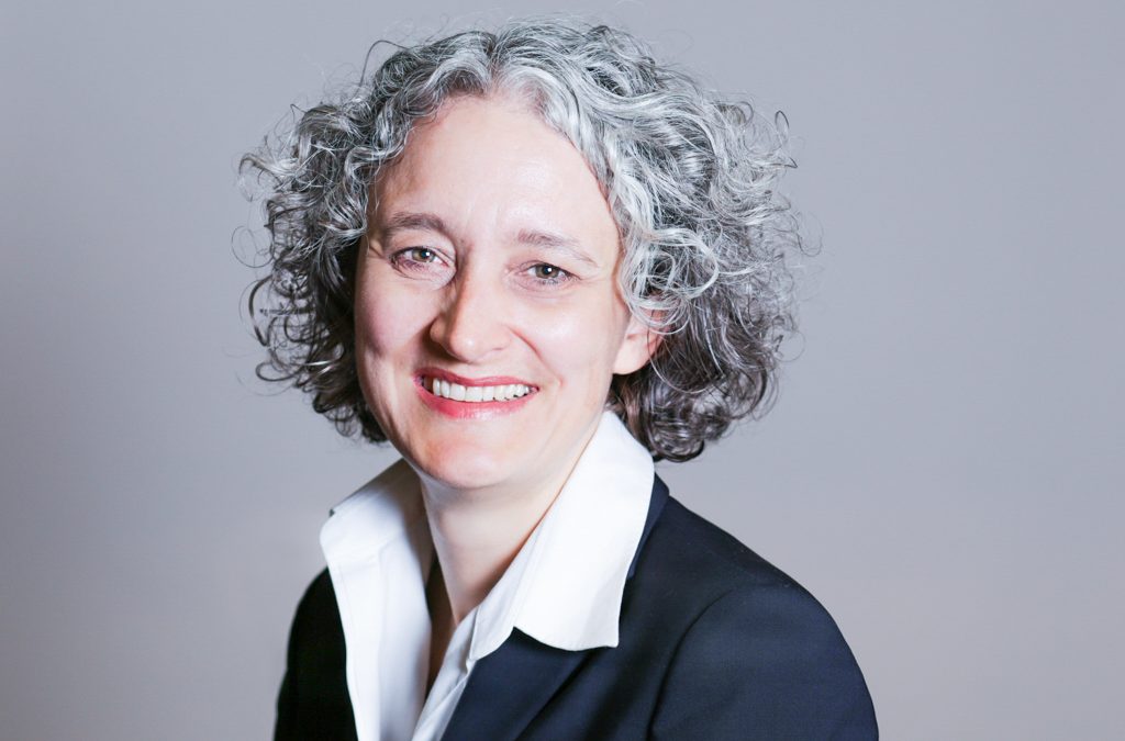 woman with grey hair standing in front of a grey backdrop